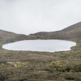Biserică veche de piatră pe o culme verde, cu un munte înzăpezit din Caucaz în fundal