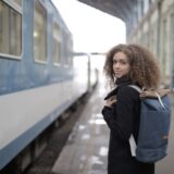 Turist îngrijorat care își caută actele în rucsac pe peronul unei gări aglomerate