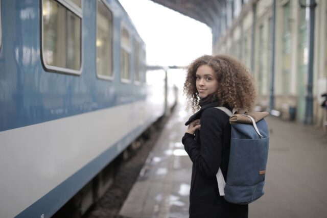 Turist îngrijorat care își caută actele în rucsac pe peronul unei gări aglomerate