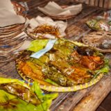 Tarabă dintr-o piață în aer liber, cu roșii, ardei, ierburi aromatice și legume proaspete de sezon